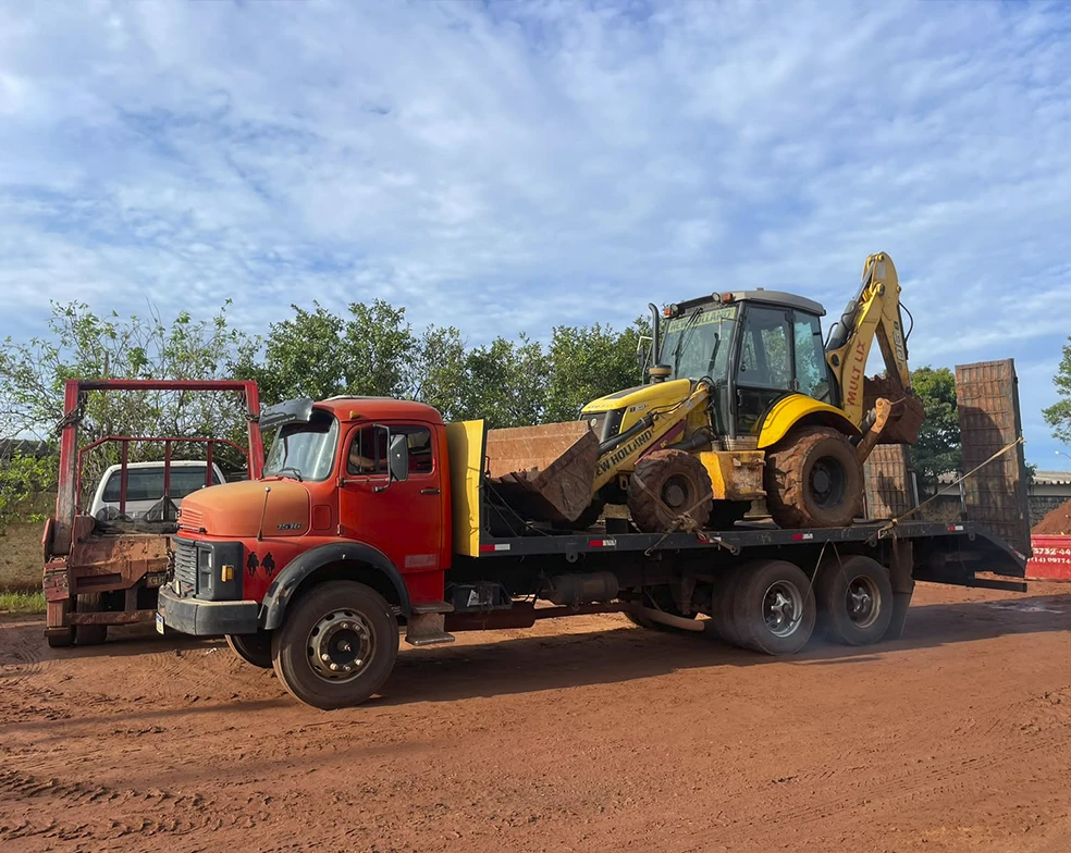 Caminhão prancha truck da Mult Lix realizando o transporte de retroescavadeira amarela para obras na região de Avaré.