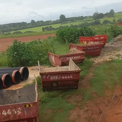 Várias caçambas estacionárias vermelhas da Mult Lix organizadas em área verde na zona rural de Avaré.