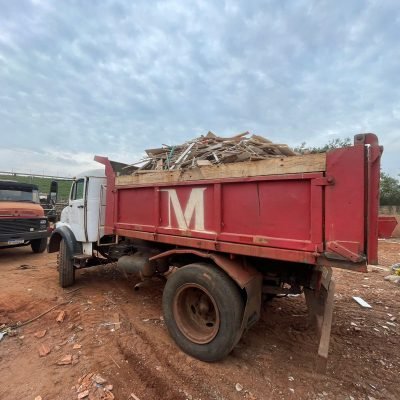 Caminhão basculante trucado vermelho da Mult Lix estacionado em canteiro de obras carregado com entulho de demolição.