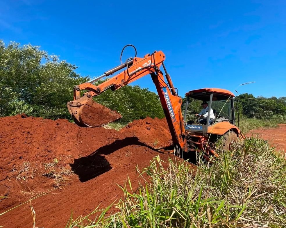 Retroescavadeira amarela e caminhão basculante da Mult Lix trabalhando em canteiro de obras na cidade de Avaré.
