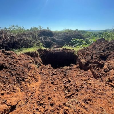 Vista superior de escavação profunda em solo arenoso para fundação de residência e subsolo.