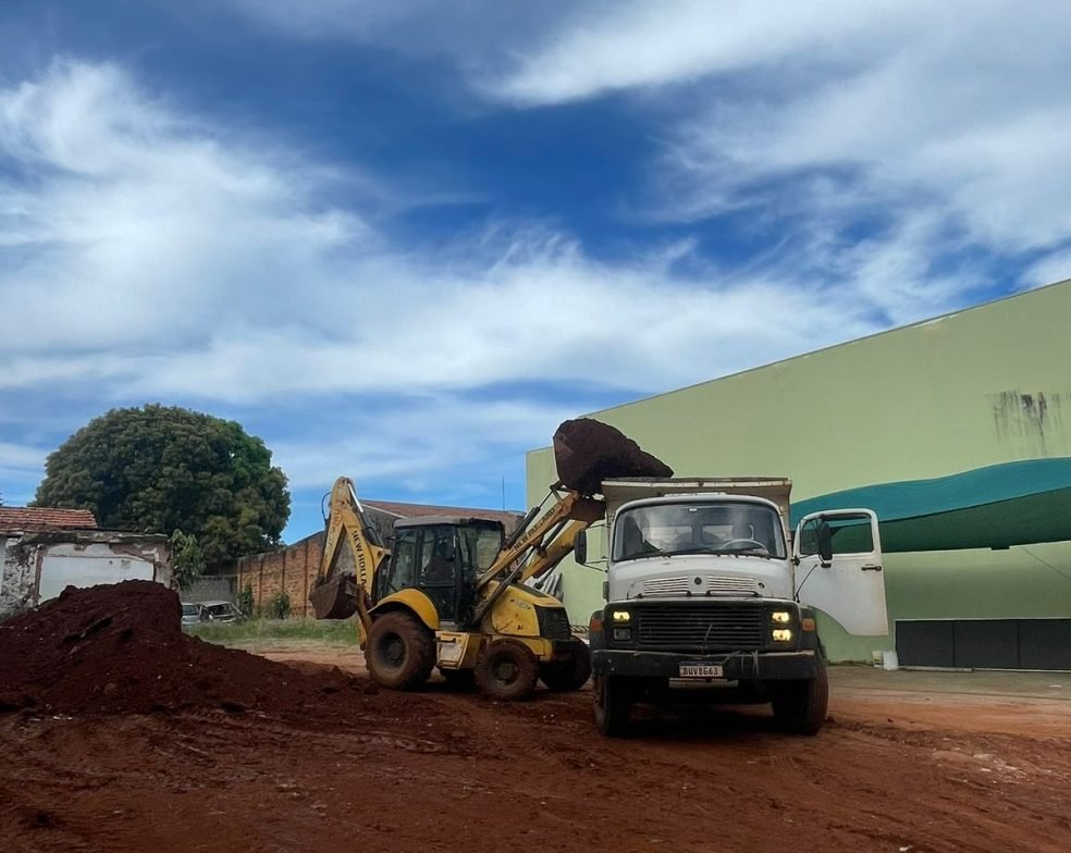 Retroescavadeira amarela e caminhão basculante da Mult Lix trabalhando em canteiro de obras na cidade de Avaré.
