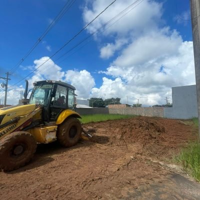 Retroescavadeira amarela operando na movimentação e nivelamento de terra vermelha em terreno urbano na região de Avaré.