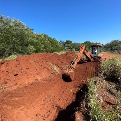 Escavadeira operando em terreno inclinado para realizar o corte de terra e nivelamento de platô em Arandu.